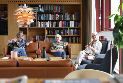 Tre damer som sitter i sofaen i stuen på vålandstun for den daglige morgenkaffen.