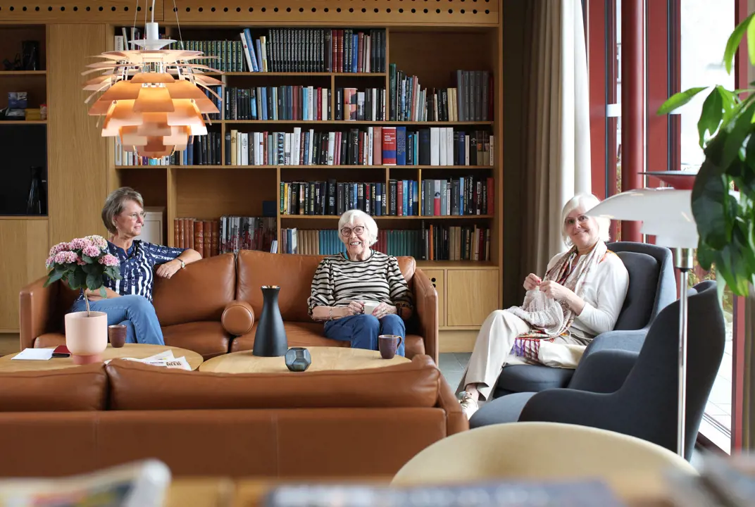 Fra venstre, Bente Hopland, Vårinn Hauan og Randi Morvik trives med det daglige sosiale møtepunktet, morgenkaffen. Tre damer som sitter i sofaen i stuen på vålandstun for den daglige morgenkaffen.