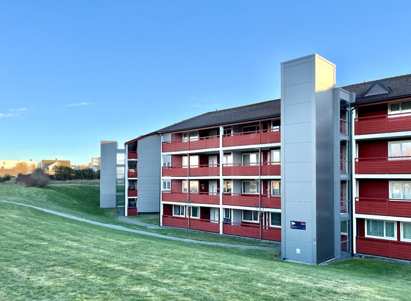 Bildet viser Mjughaug terrasse fra utsiden. Bak hvor vi ser heisene som er koblet på bygget med de grå heissjaktene. 