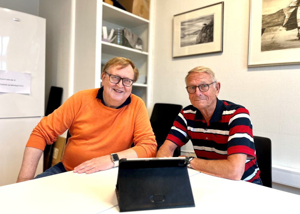 Bildet viser Kjell Carlsen og Åge Skogen som er frivillige data hjelpere. De sitter ved siden av hverandre ved et bord, med et nettbrett foran seg.