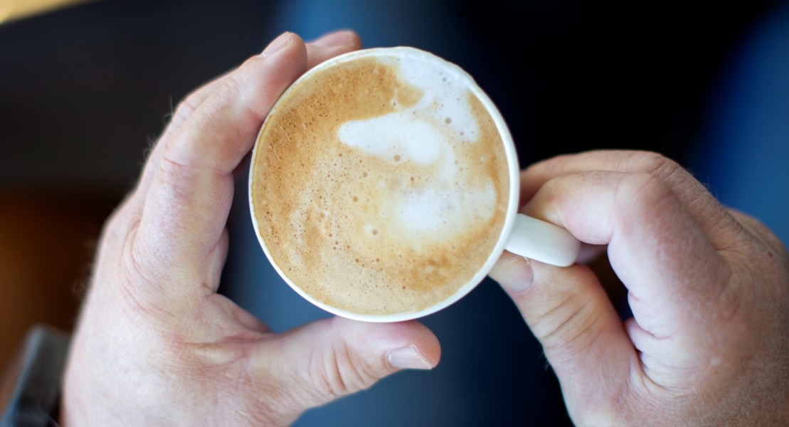Bildet viser to hender som holder en koppe kaffe mellom hendene. 