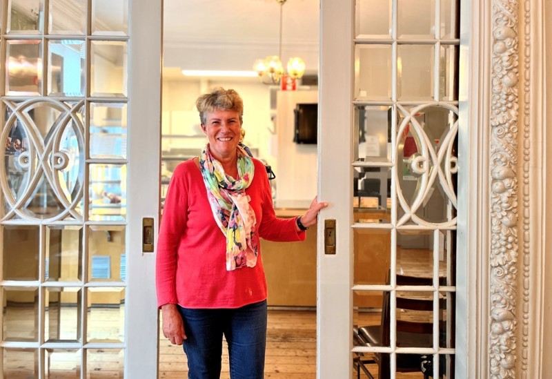 Vi ser et bilde Brit Bjørkli som driver Tante Emmas Hus. Hun står i døråpningen inn til kafeen.