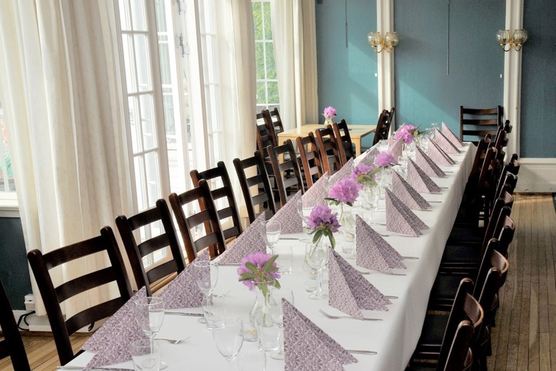 Vi ser et flott oppdekket bord med hvit duk og servietter i stuen på Tante Emmas hus.