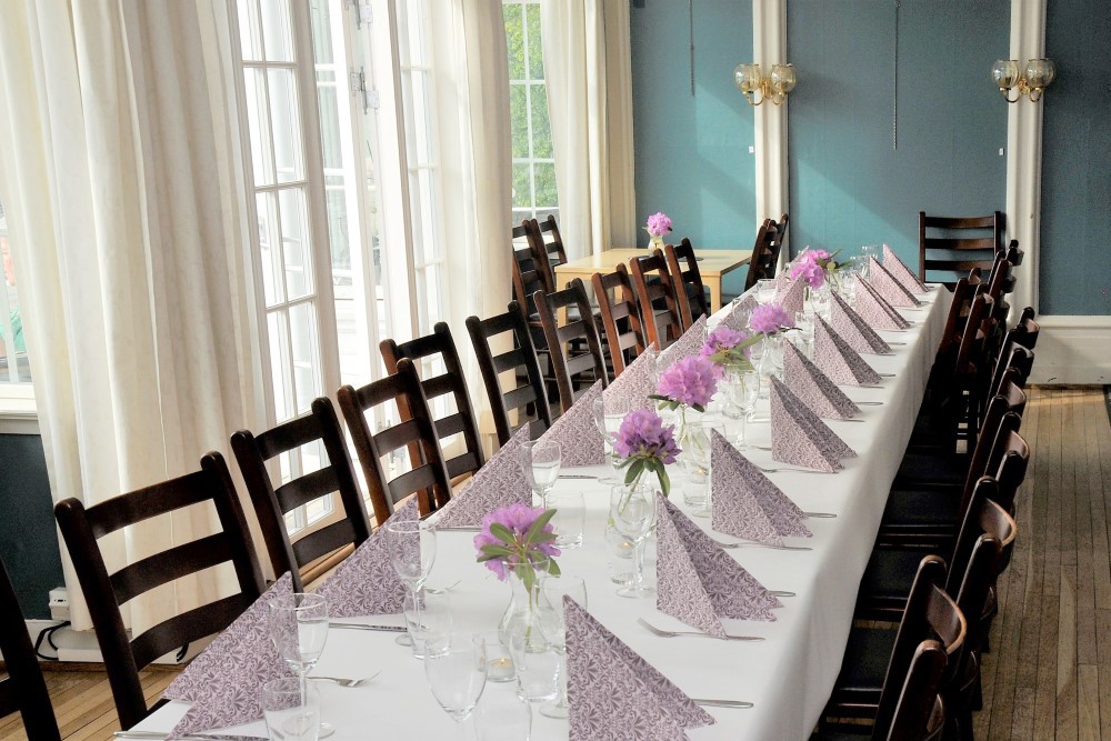 Vi ser et flott oppdekket bord med hvit duk og servietter i stuen på Tante Emmas hus.