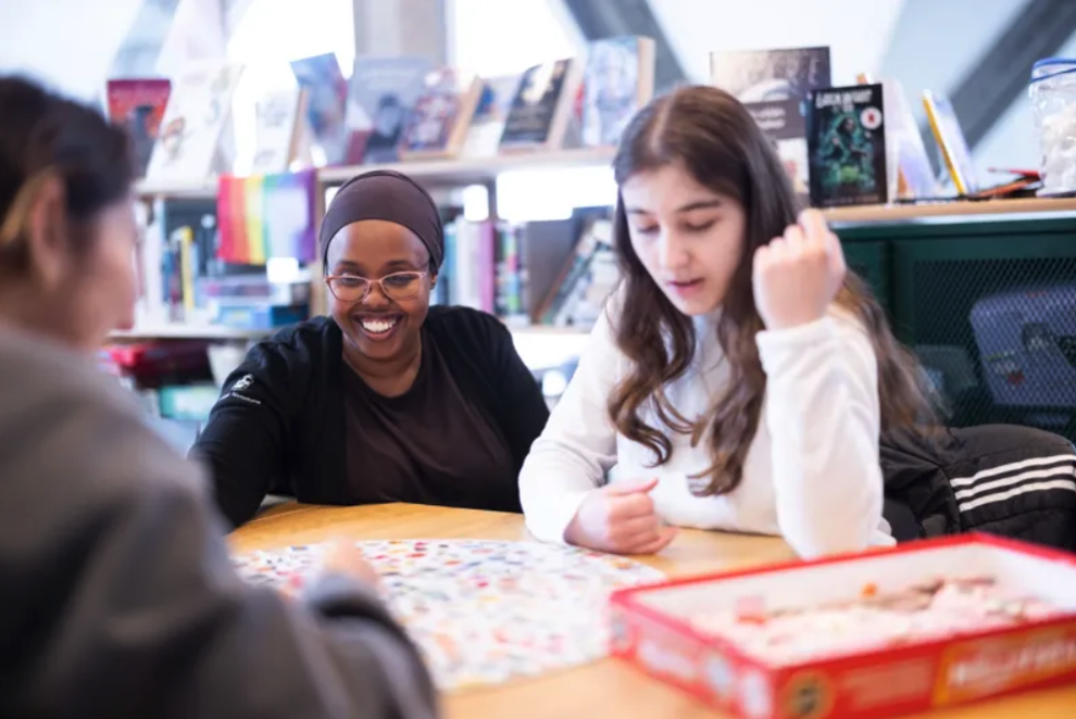 Dame hjelper en ungdom med et puslespill. Foto: Sølvberget.