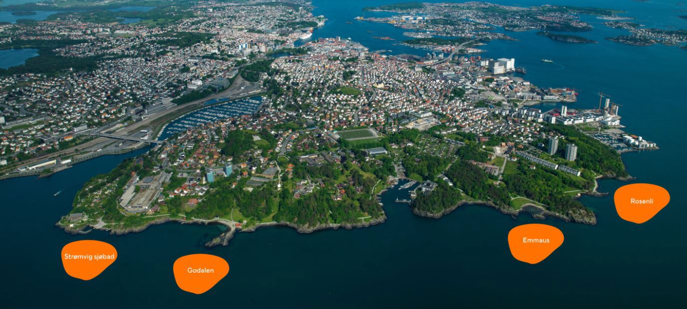 Flyfoto av torvei i det grønne langs kysten, i bakgrunnen boliger og byen.