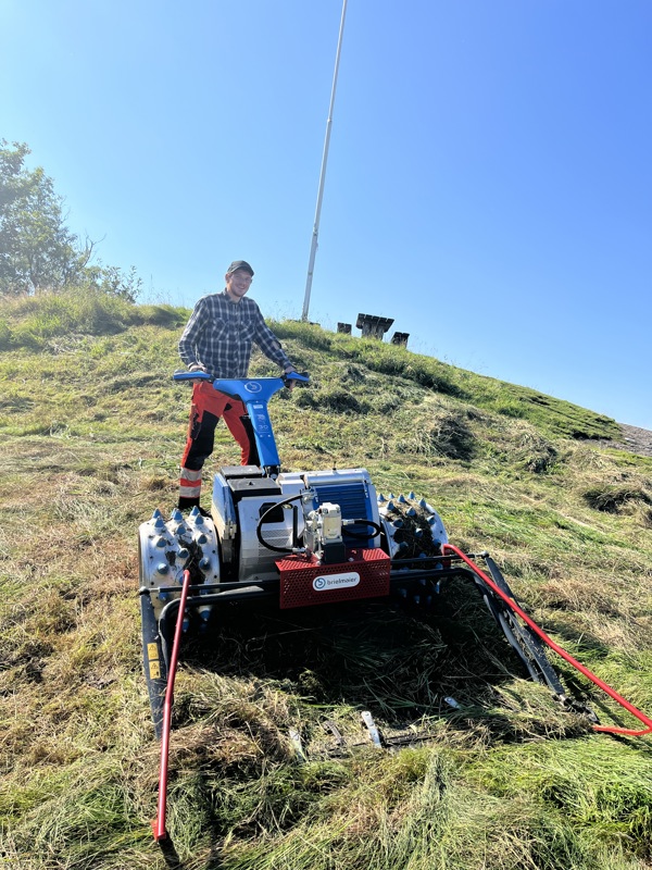 Vemund Hilde står med en stor blå gressklipper