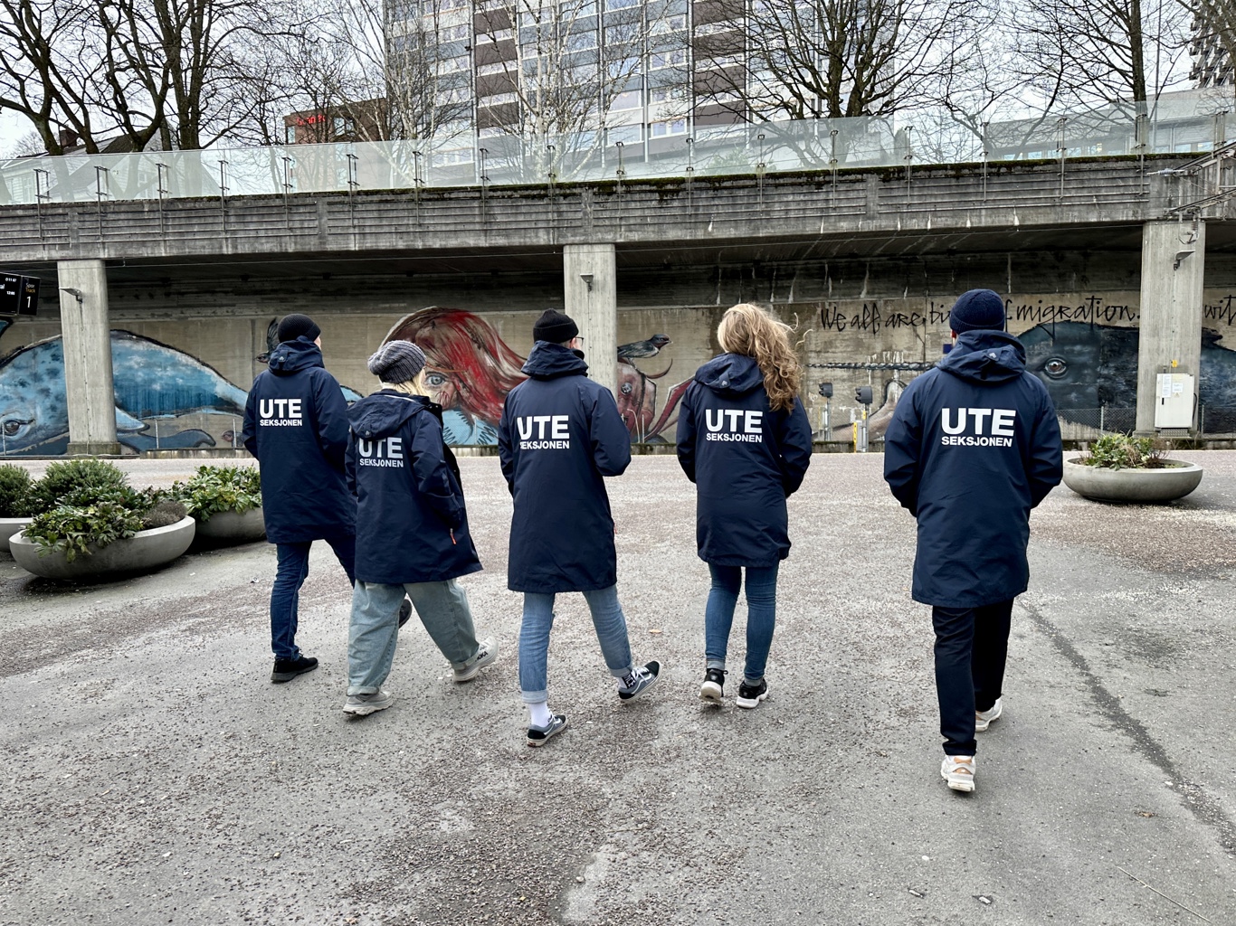 Ansatte i Uteseksjonen sett bakfra kledd i jakker med navn Uteseksjon på
