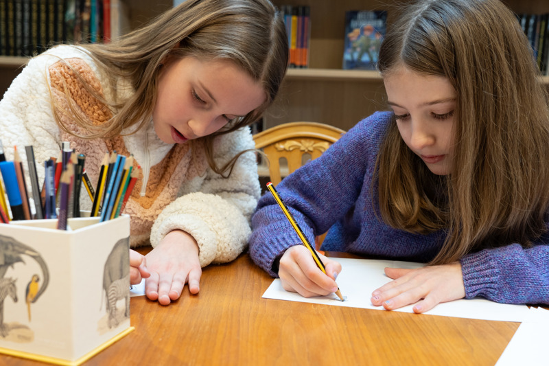 Bilde av to jenter som skriver ved ett bord under Saga skriveliga på Sølvberget.