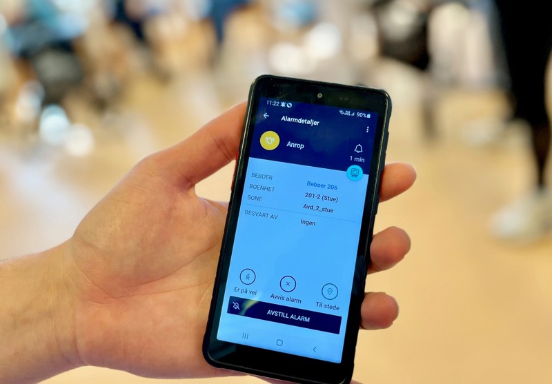 Bildet viser en telefon med en melding på skjermen som beskriver hvor en pasient som trenger hjelp befinner seg.