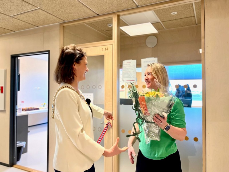 Vi ser to personer. Den ene gir en blomsterbukett til den andre for å feire.