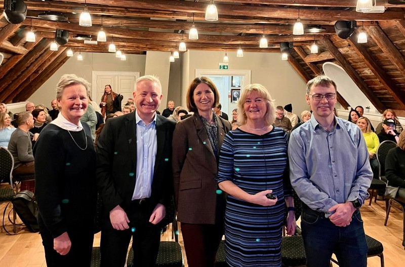 Bildet viser Inger Tone Ødegård og Harald Minge i Næringsforeningen var vertskap for dagen. Sammen med Anneline Teigen i NAV Rogaland, Ordfører Sissel Knutsen Hegdal og prosjektkoordinator Rune Endresen. De står vendt mot kamera, alle smiler og vi ser mange folk i salen bak dem. 

