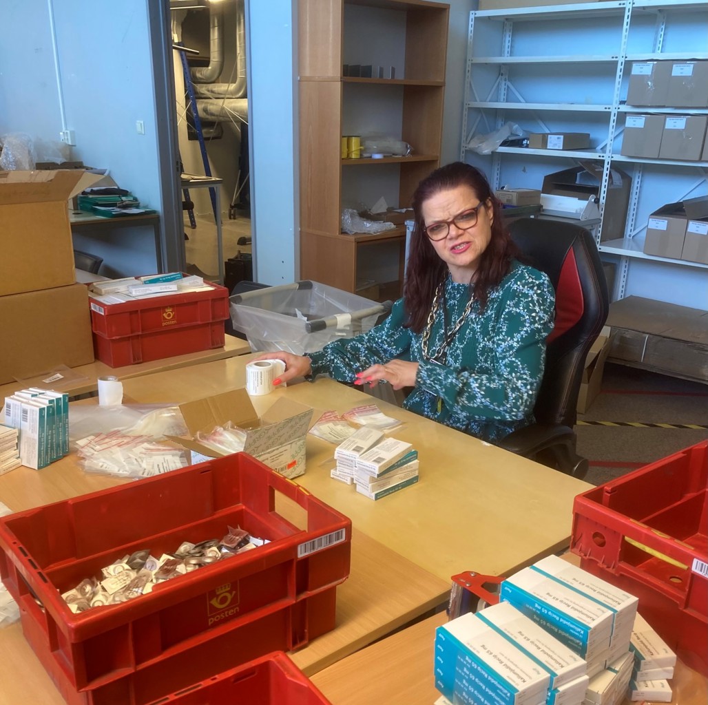 PAKKES i POSER: Elisabeth er en av flere i Attende som har pakket jodtabletter i små poser for utkjøring til skoler og barnehager. Elisabeth hos Attende pakker jodtabletter i små plastposer. Elisabeth har mørkt langt hår og briller.
