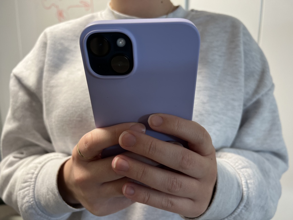 Bildet viser en ung person som taster på en rosa mobiltelefon