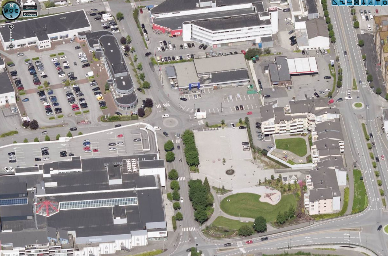 Flyfoto av hvordan det ut i Hillevåg sentrum i dag: mye asfalt, bilveier og parkeringsplasser. 