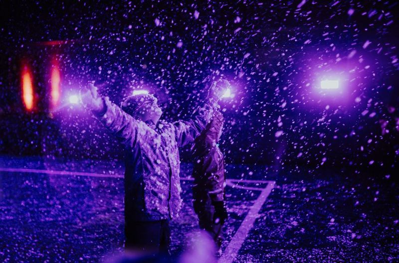 Et barn som strekker hendene i været,  i lilla lys. Foto: Line Owren