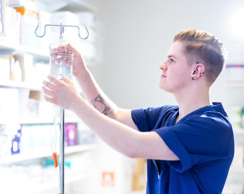 Sykepleier med intravenøs-stativ