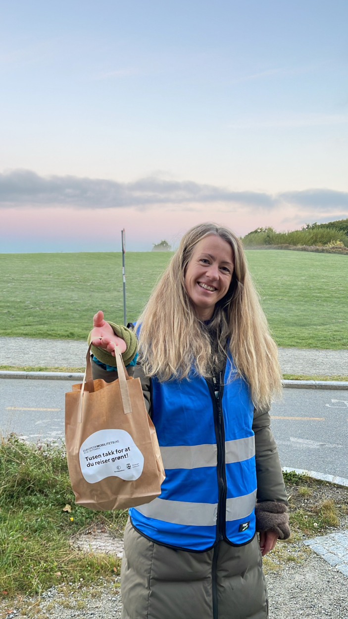 Bilde av Imme Dirks Eskeland, mobilitetsrådgiver i Klima- og miljøavdelingen, og prosjektleder for InterReg-prosjektet i Stavanger kommune. Hun smiler og holder en frokostpose som hun skal dele ut til syklister.