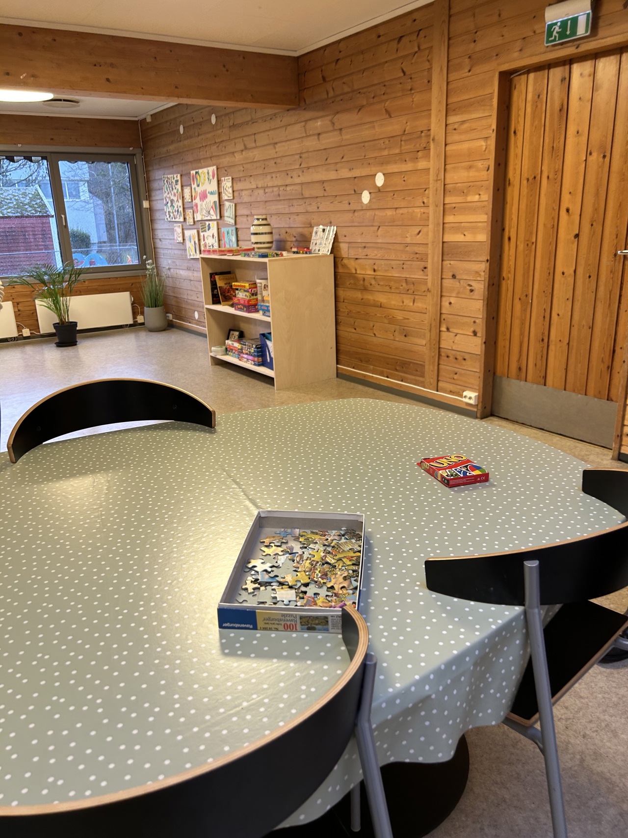 Svarte stoler og bord med grønn duk med brettspill og puslespill på.