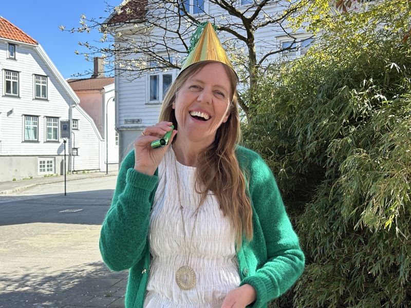 Jane Nilsen Ålhus smiler med partyhatt på hodet og fløyte i hånda.