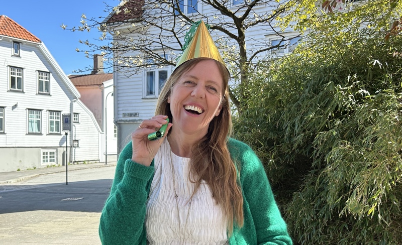 Jane Nilsen Aalhus smiler med partyhatt på hodet og fløyte i hånda.