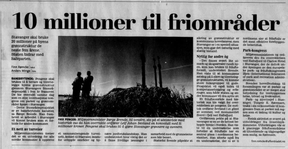 Avisutklipp med svart-hvitt-bilde av to menn, daværende miljøvernminister Børge Brende og ordføre Leif Johan Sevland, som står med monumentet "De tre sverd" i Hafrsfjord