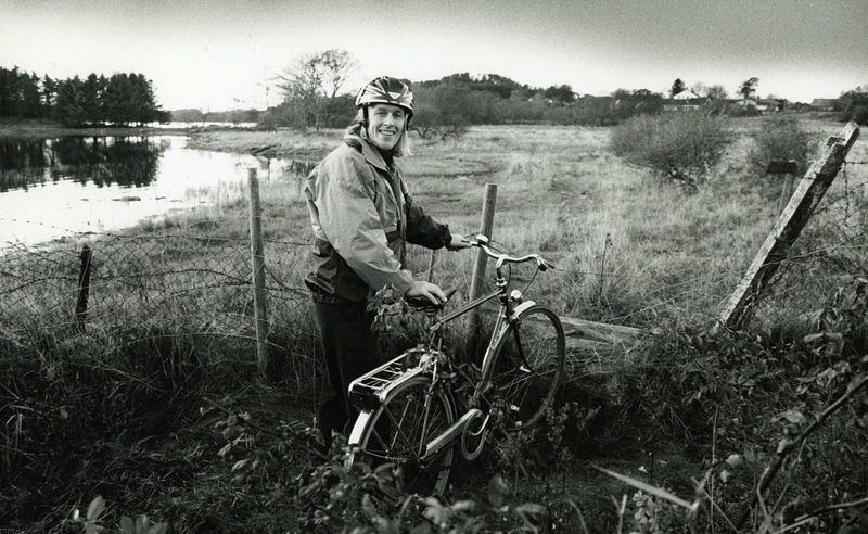 Mann med sykkel stanset av et gjerde ved et vann