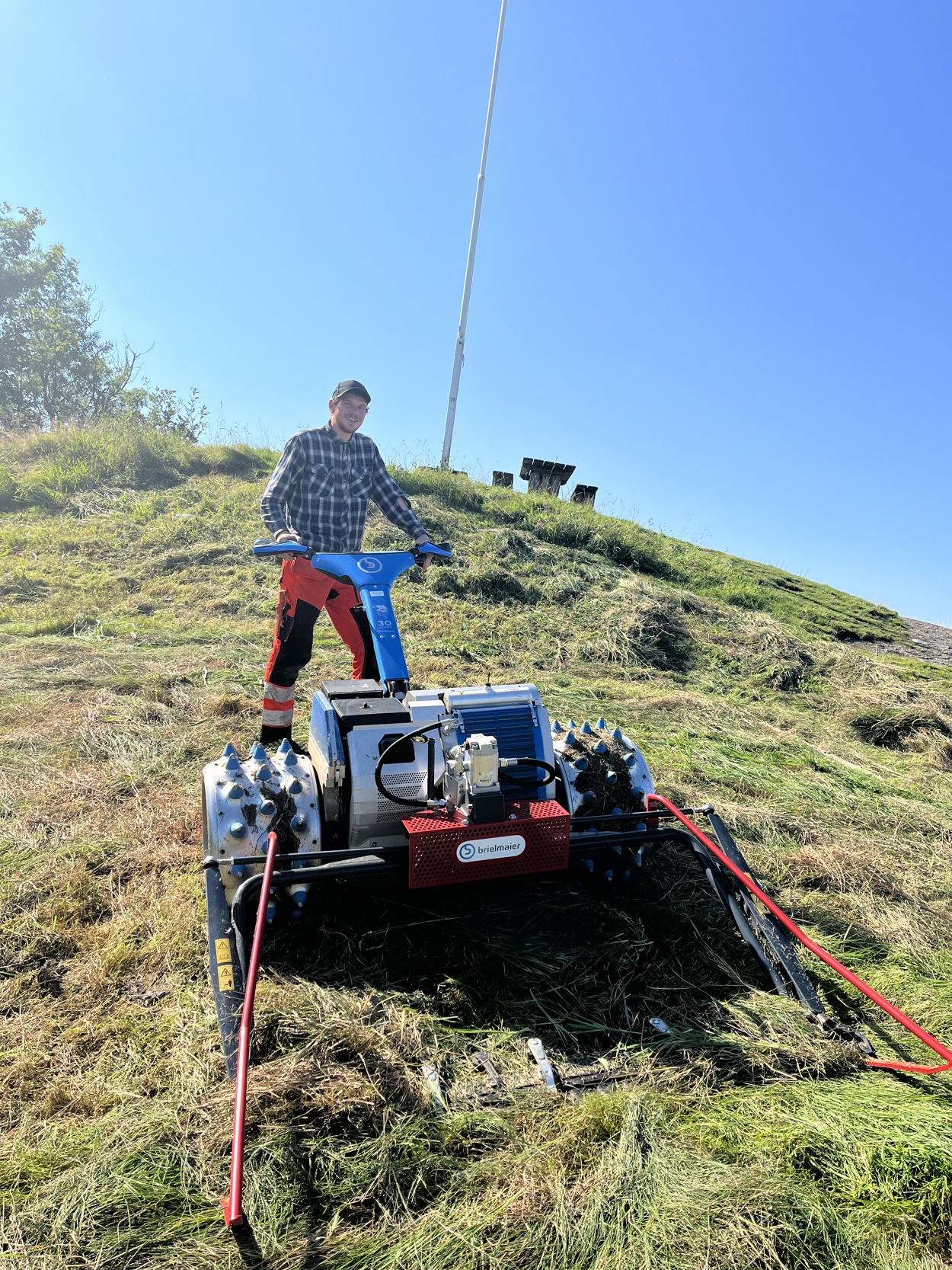 Vemund Hilde står med en stor blå gressklipper