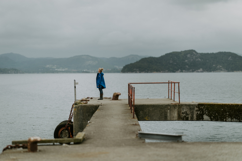 Kvinne i blå jakke står på Hetlandskaien og ser utover