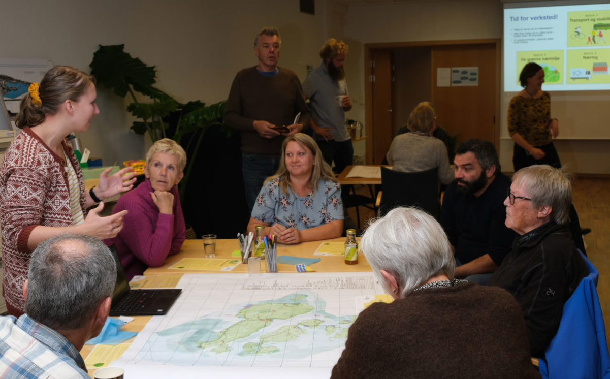 Bilde fra planverksted i Vikevåg, folk sitter rundt border og jobber rundt et kart over kommunedelen. 