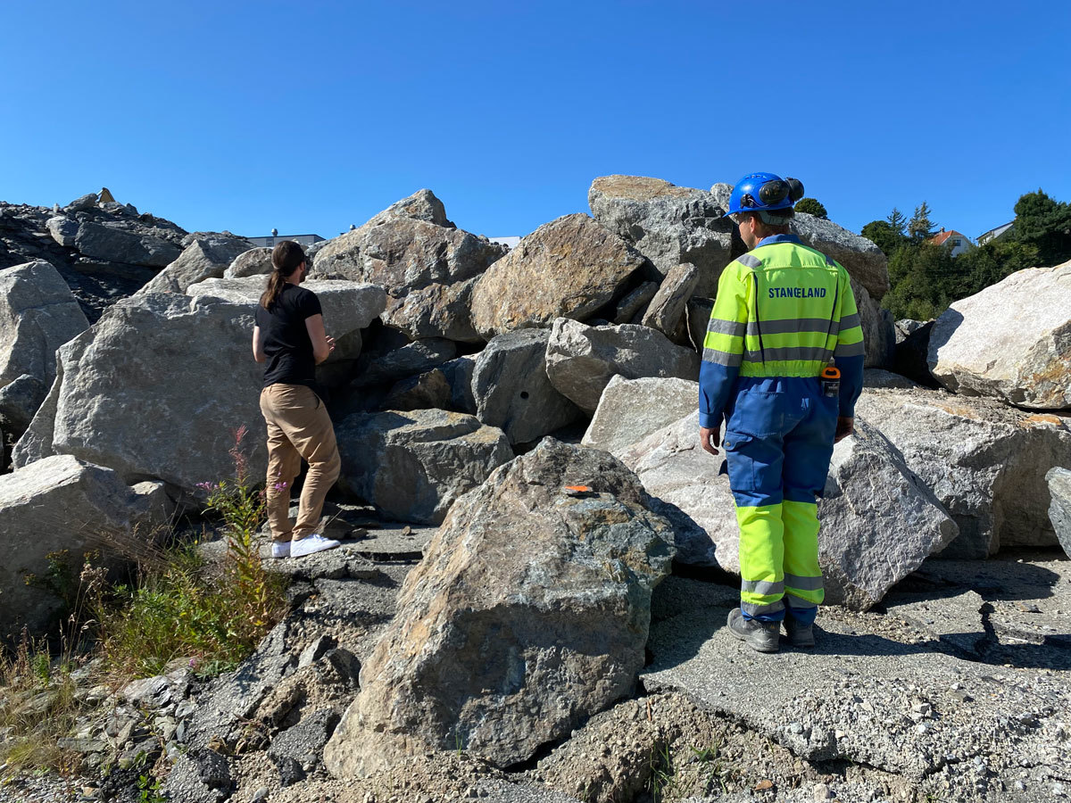 Hva kan disse steinene brukes til? Bilde av to personer i steinene i sjøkanten på Kvalaberg. 