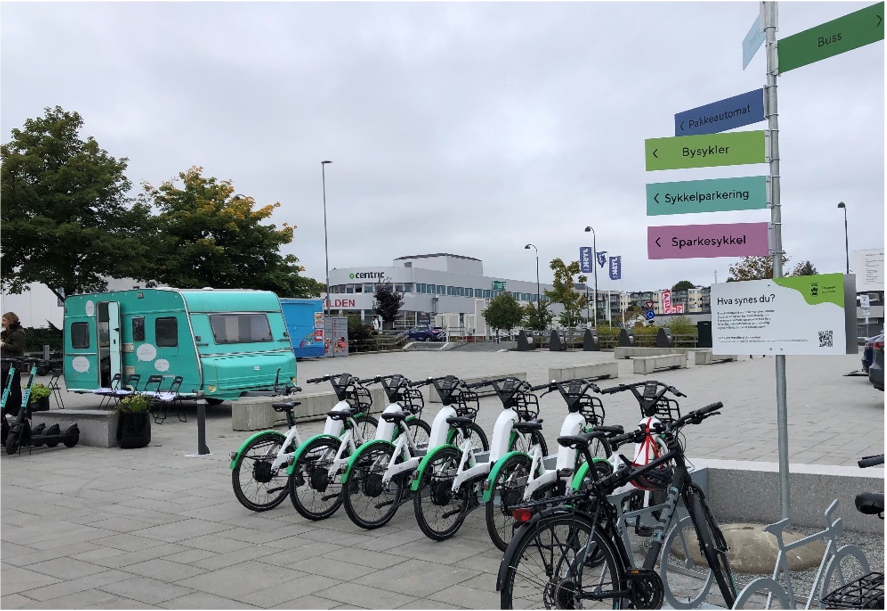 Mobilitetspunkt på Hillevåg torg. Bysykler, sparkesykler, sykkelparkering, pakkeautomat og buss samlet på ett sted.