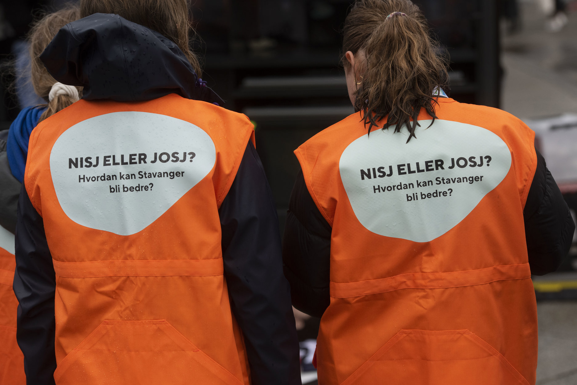 To damer som står med ryggen til. På seg har de budskapet: ude på? Snakk med oss om hverdagen din.