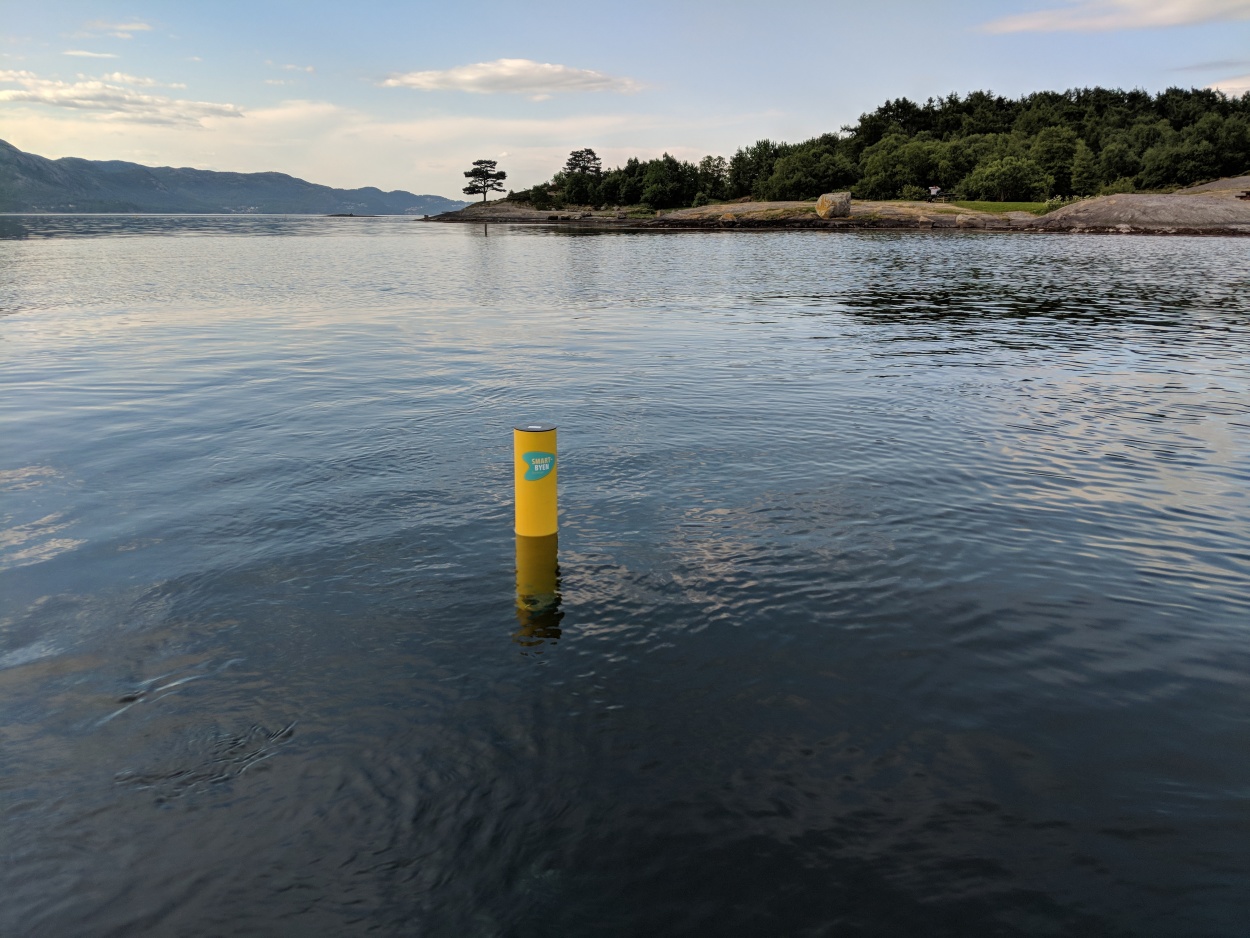 En gul sylinderformet gjenstand med smartby-logo er plassert ute i sjøen på Vaulen badeplass.