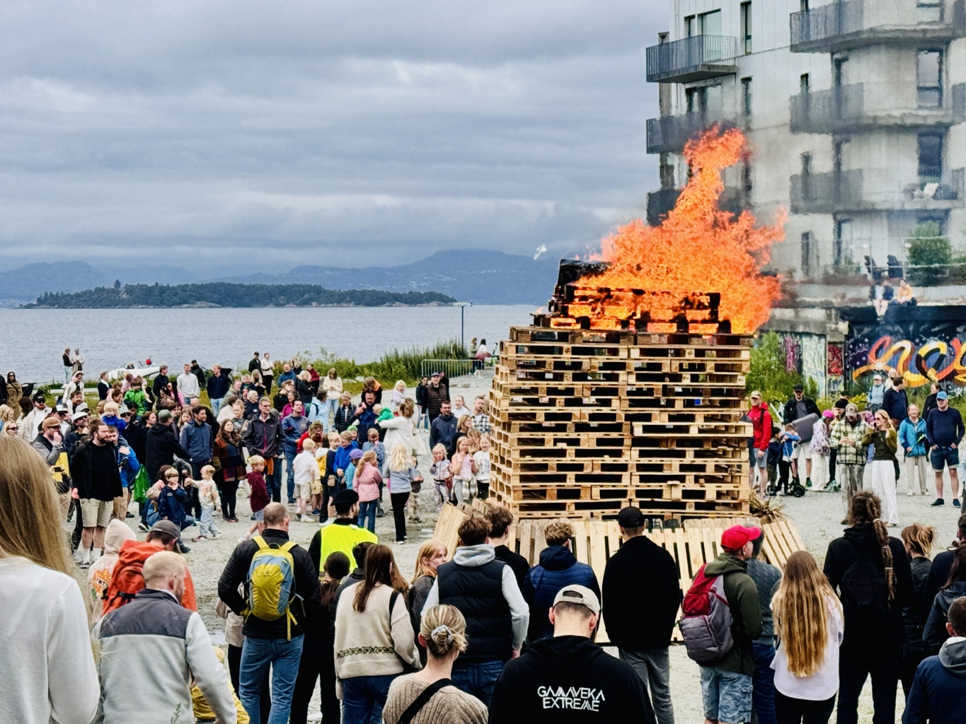 Sankthans-feiringen ved Tou scene i 2024. sankthansbål med mange folk som ser på. Deler av Tou scene til høyre i bildet.