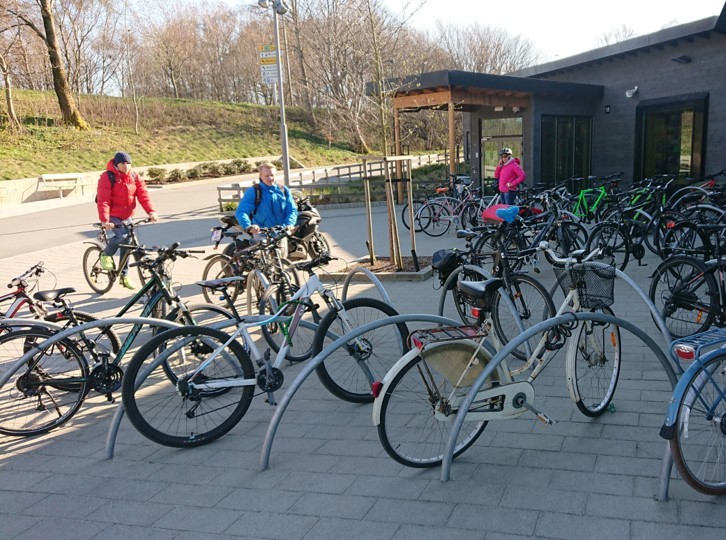 Mange sykler parkerer i sykkelstativer som ser ut som en bøyle ved siden av inngangen til svømmehallen Gamlingen i Stavanger.