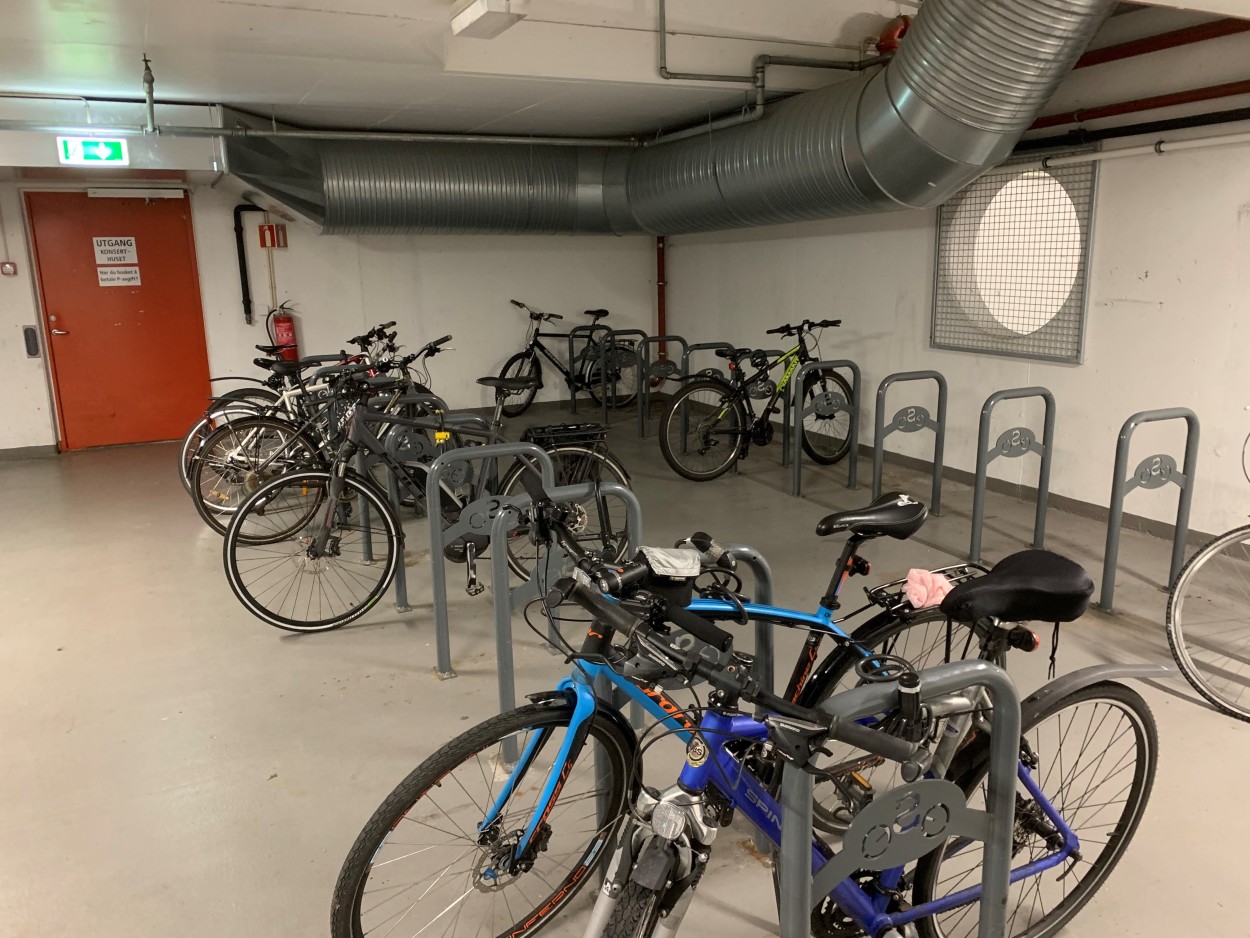 I et rom står flere sykler parkert og låst fast i sykkelstativer.