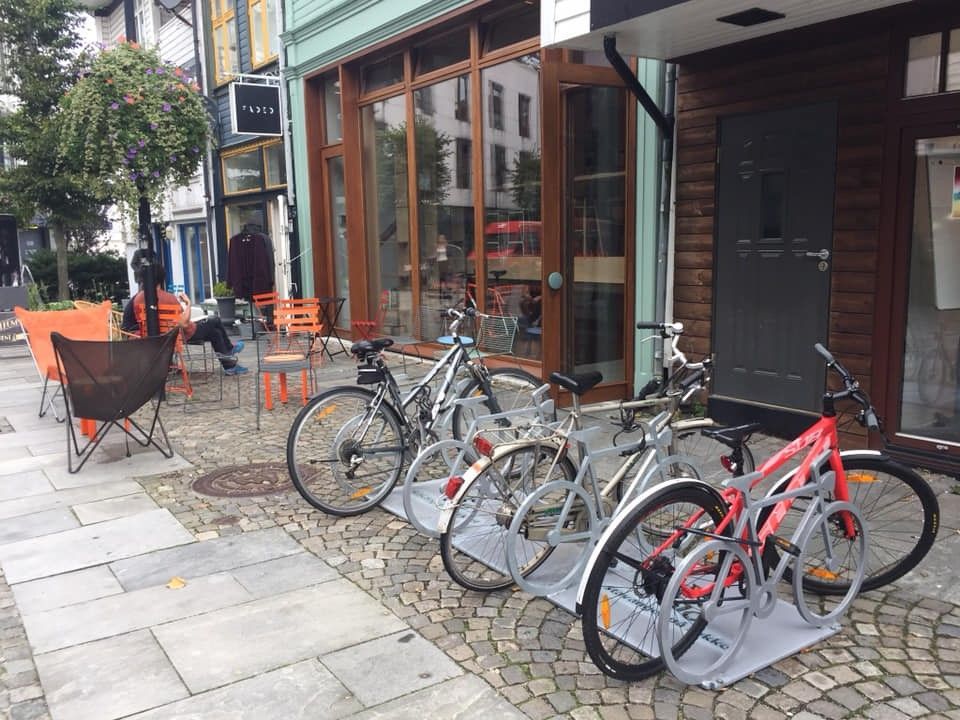 Utenfor en forretning i Stavanger sentrum står tre sykler låst fast i sykkelstativer som ser selv ut som sykler.