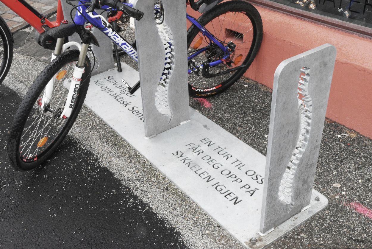 To sykler står låst fast i en sykkelstativ, spesialdesignet til Stavanger Kiropraktisk senter