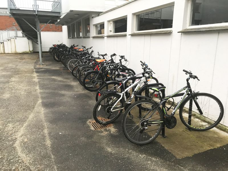 Mange barnesykler står parkert i stativer langs en husvegg foran Tastaveden ungdomsskole i Stavanger.